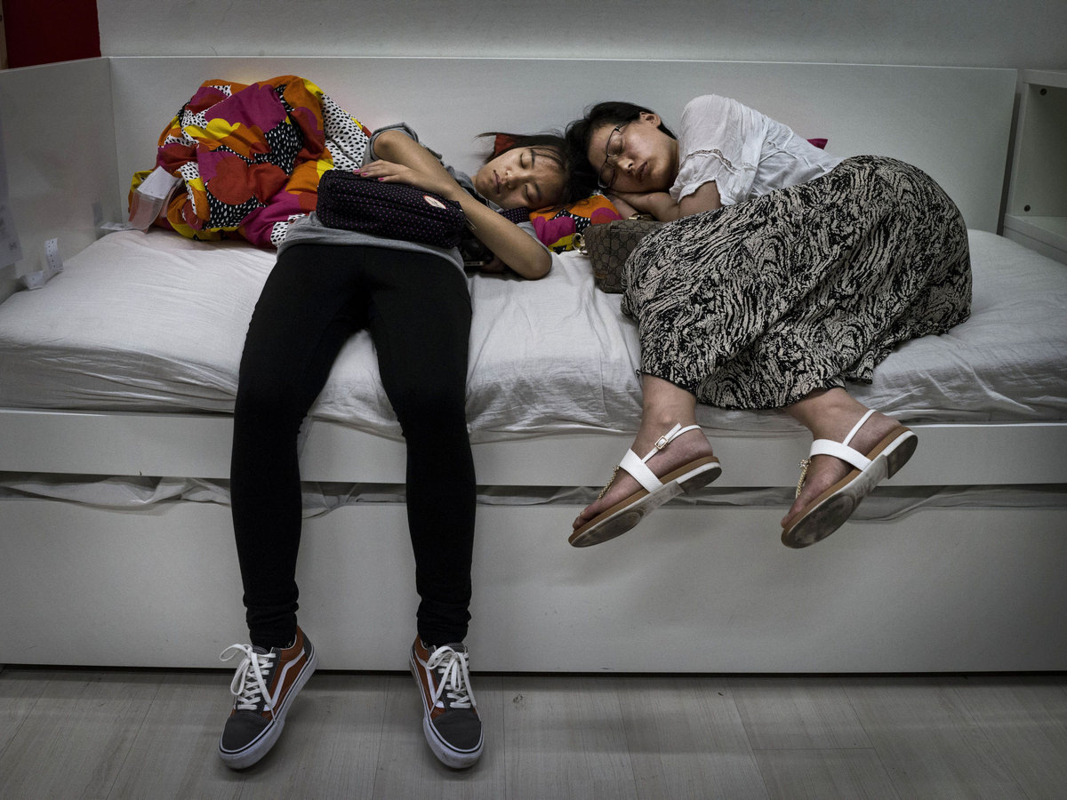 Women Sleeping On A Display Bed In An Ikea Showroom