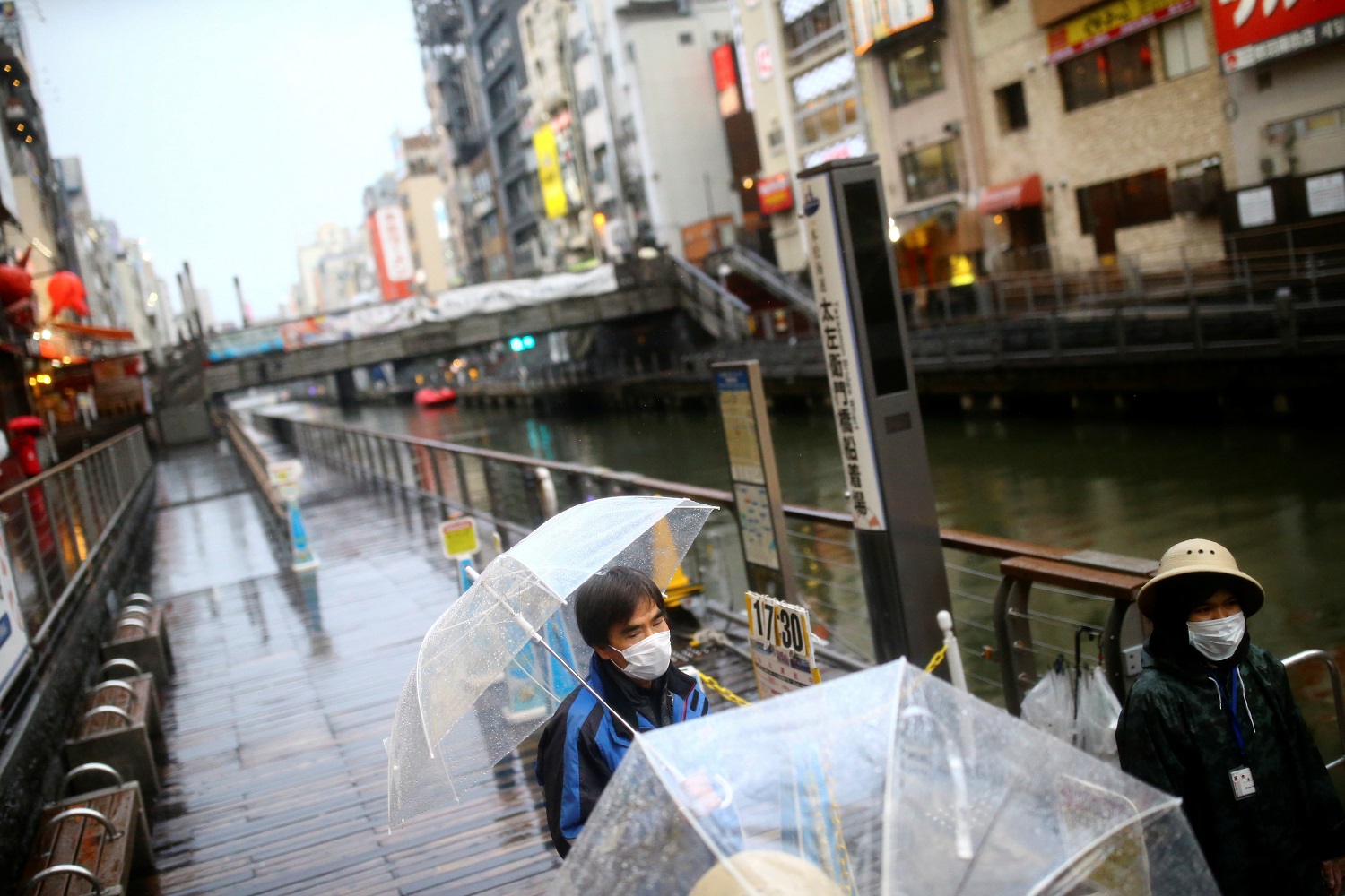 Workers, wearing protective masks following an outbreak of the coronavirus disease (COVID-19), receive tourists on an almost empty port in the Dotonbori entertainment district of Osaka