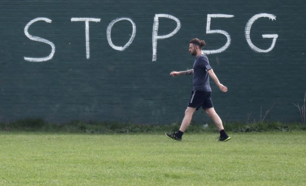 A man exercising during lockdown to combat an outbreak of coronavirus disease (COVID-19) walks past a graffiti that reads 