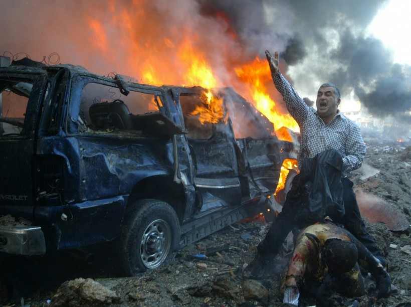 A Lebanese man shouts for help for a wounded man near the site of a car bomb explosion in Beirut