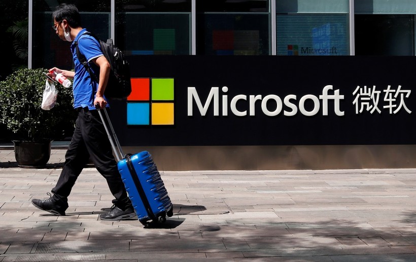 A person walks past a Microsoft logo at the Microsoft office in Beijing