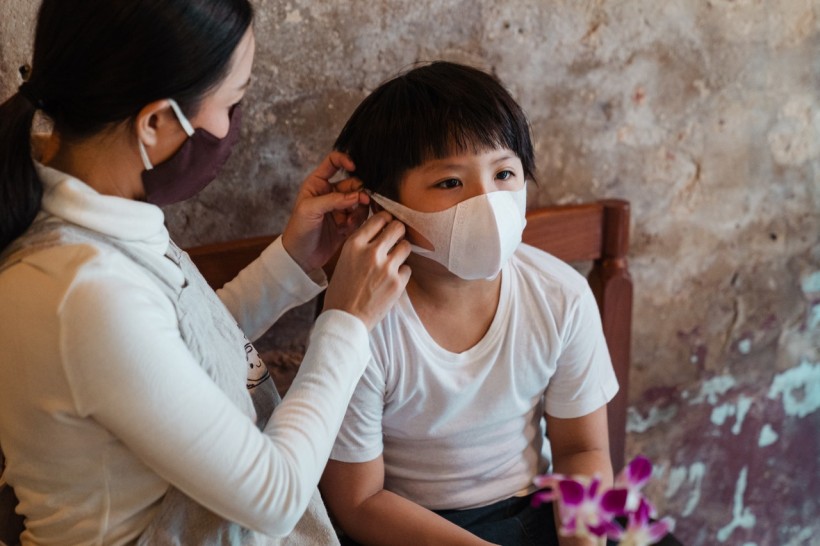Woman Putting a Face Mask on a Child