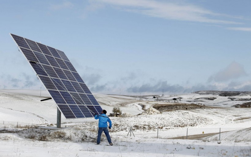 A man cleans solar panels covered by sno