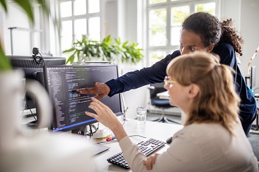 Businesswomen discussing coding on computer - stock photo